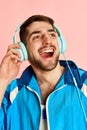 Half-length portrait of smiling young handsome man in headphones and sportswear posing against pink studio background Royalty Free Stock Photo