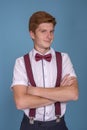 Half length  portrait of a  stylish red-haired young smiling man with arms crossed against  blue background in the studio Royalty Free Stock Photo