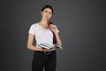 Half length portrait of thougtful dreamy woman holding red pen in hand near mouth, books in other hand Royalty Free Stock Photo