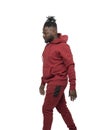 Dark skinned African man with pigtails in a ponytail and beard wearing burgundy tracksuit walking isolated