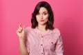 Half length portrait of woman showing small amount of something and having sneering facial expression, posing isolated over rosy