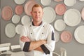 Young handsome tall redhead blue-eyed men chef cook stands with his arms crossed against the background of the wall of his Royalty Free Stock Photo