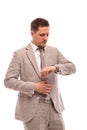 Half length portrait of a young serious man wearing beige suit , isolated. He looks at his watch Royalty Free Stock Photo