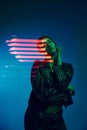 Half-length portrait of young stylish woman posing over dark blue background with neon mixed light lines. Concept of Royalty Free Stock Photo