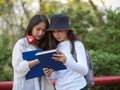 Half-length portraits of two young pretty female teenagers reading book together Royalty Free Stock Photo