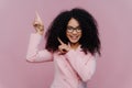 Half length shot of cheerful Afro American woman with dark bushy hairstyle, wears violet suit, points above with both index Royalty Free Stock Photo