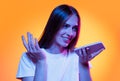 Half-length shot of emotional girl with long glossy dark hair isolated on orange background in neon light. Concept of Royalty Free Stock Photo