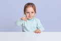 Half length studio photo of charming little girl wearing casually, pointing directly at camera, showing something to her mother, Royalty Free Stock Photo