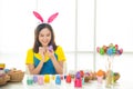 Half length studio shot of asian beauty happy young woman wearing bunny ears and holding colorful Easter egg in wood basket with Royalty Free Stock Photo