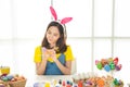 Half length studio shot of asian beauty happy young woman wearing bunny ears and holding colorful Easter egg in wood basket with Royalty Free Stock Photo