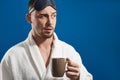 Half length of young handsome man keeping mug with beverage in arm Royalty Free Stock Photo