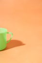 A half of a light green plastic cup sits on an orange background Royalty Free Stock Photo