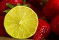 Half lime surounded by strawberries Royalty Free Stock Photo