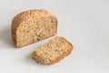 Half a loaf of homemade whole grain bread with various seeds and two slices on a white background Royalty Free Stock Photo