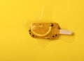 a half melted passion fruit flavor popsicle with slice of orange on a yellow background Royalty Free Stock Photo