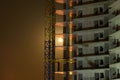 Half of moon disk shines through the concrete construction of new multi-storey building. Autumn night in the construction site.