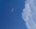 Half moon in the evening sky next to the fluffy clouds Royalty Free Stock Photo