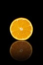 Half orange on a black reflective background Royalty Free Stock Photo