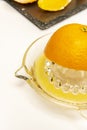 Half orange in glass hand squeezer with juice on white surface Royalty Free Stock Photo