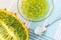 Half of orange kiwano cucumis metuliferus, horned melon, glass bowl with kiwano pulp and a spoon on a tablecloth. Fruits,