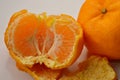 Half of a peeled mandarin orange (Lukan variety) and skin against white background