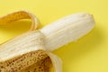 Half peeled ripe banana macro on yellow background Royalty Free Stock Photo