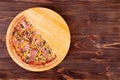 Half of pizza with chicken breast, corn, bacon and mushrooms, on a round wooden plate which is on wood rustic table Royalty Free Stock Photo