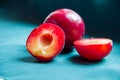 Half plums on a background of whole plums on the green fabric.