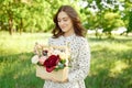 Half portrait of a charming positive woman dressed in long white summer dresses with a happy smile on the background of a green Royalty Free Stock Photo