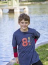 Half portrait of a smiling eight year old boy by a lake