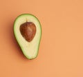 Half ripe green avocado with a brown bone on an abstract orange background