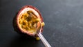 Delicious fresh juicy passionfruit, maracuja half with spoon closeup, dark background.