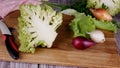 Half of Roman Romanesque cabbage Romanesco on a cutting board next to other vegetables and a knife.