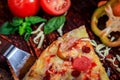 Half slice of delicious homemade pizza with salami, ham, hot sausage and mozzarella cheese with fresh vegetables as decor Royalty Free Stock Photo