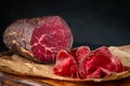 Half a smoked bresaola and cut pieces on a chopping Board. Italian Antipasti Royalty Free Stock Photo