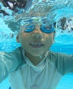 Half submerged 4 year old asian boy playing in pool