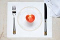 Half a tomato in the form of a heart on a painted plate. Concept of vegetarian food. Restrictions on food. Small portion of food o Royalty Free Stock Photo