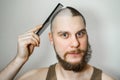 Half trimmed bald guy on isolated background. man hold comb and clipper. Concept of hair loss, alopecia, transplantation Royalty Free Stock Photo