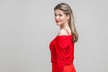 Half turn portrait of gorgeous elegant young woman in red dress, isolated on gray background Royalty Free Stock Photo