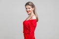 Half turn portrait of happy elegant young lady with neat hairstyle and in red dress. isolated on gray background Royalty Free Stock Photo