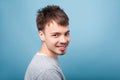 Half turned portrait of positive handsome brunette man looking at camera with toothy smile. indoor studio shot isolated on blue Royalty Free Stock Photo