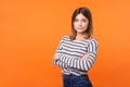 Half-turned portrait of serious young woman with brown hair in long sleeve striped shirt. isolated on orange background Royalty Free Stock Photo
