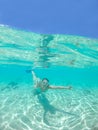 HALF UNDERWATER: Cheerful young woman makes a hand gesture while snorkeling.