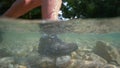 HALF UNDERWATER: Unrecognizable female hiker steps into the refreshing stream.