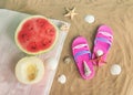 Half of watermelon and melon, flip flops, starfishes and seashells on towel on sand beach. Top view Royalty Free Stock Photo