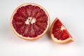 Half and wedge of red blood sicilian orange isolated on white