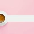 Half of white cup with coffee with frothy crema on saucer on light pink background. Design template with graphic elements