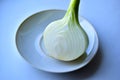 Half a white onion on a white plate on the windowsill Royalty Free Stock Photo