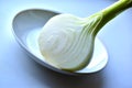 Half a white onion on a white plate on the windowsill Royalty Free Stock Photo