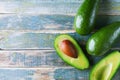 Half and whole avocado on vintage wooden table top view. Organic wellness food background. Copy space.